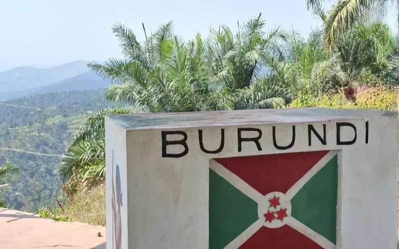 A white wall with Burundi and the Burundian flag on it, overlooking a valley