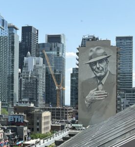 A city view of Montreal with a mural of Leonard Cohen on the side of a building