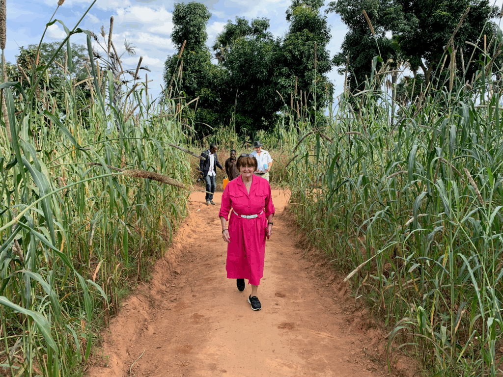 Baroness Caroline Cox walks on a dusty path through a crop field