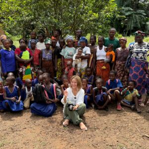 Judy sits on the ground surrounded by self-help group members dressed in brightly coloured clothes